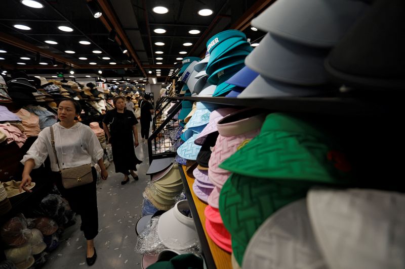 © Reuters. Shoppers walk past sun protection headgear displayed at a store in a shopping mall, amid a yellow alert for heatwave in Beijing, China July 19, 2023. REUTERS/Florence Lo/File Photo