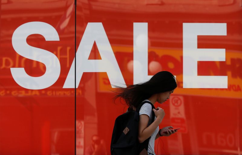 &copy; Reuters. A woman looks at her phone while walking past a sales sign on display outside a retail store in Ottawa, Ontario, Canada, July 21, 2017. REUTERS/Chris Wattie/File Photo