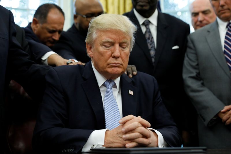 © Reuters. Faith leaders place their hands on the shoulders of U.S. President Donald Trump as he takes part in a prayer for those affected by Hurricane Harvey in the Oval Office of the White House in Washington, U.S., September 1, 2017.  REUTERS/Kevin Lamarque