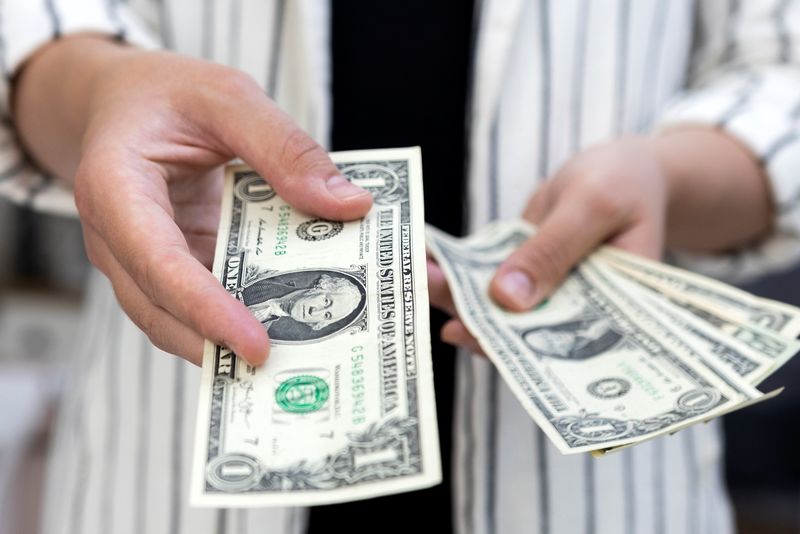 &copy; Reuters. Una donna tiene in mano delle banconote di un dollaro statunitense in questa foto del 30 maggio 2022. REUTERS/Dado Ruvic/Illustrazione/File Photo
