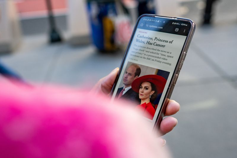 © Reuters. A person uses a cellphone to read a news article on the announcement by Britain's Catherine, Princess of Wales, that she is undergoing preventative chemotherapy after tests taken following her abdominal surgery in January revealed that cancer had been present, in New York City, U.S., March 22, 2024. REUTERS/David Dee Delgado