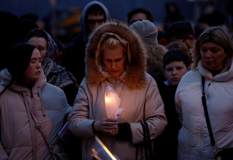 © Reuters. A woman holds a candle at a memorial to the victims of the shooting attack near Moscow, March 23, 2024. REUTERS/Maxim Shemetov