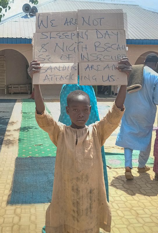 © Reuters. Un garçon tient une pancarte pour protester contre ce qu'un enseignant, un conseiller local et des parents ont déclaré être l'enlèvement de centaines d'élèves par des hommes armés après la prière du vendredi à Kaduna, au Nigéria. /Photo prise le 8 mars 2024/REUTERS