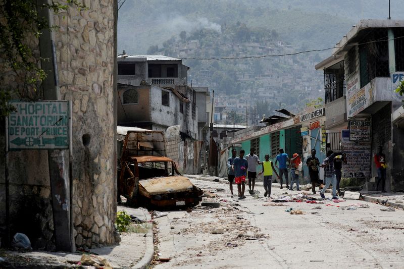 &copy; Reuters. FILE PHOTO: People walk past a damaged car in the Carrefour Feuilles neighborhood, which was deserted due to gang violence, in Port-au-Prince, Haiti March 19, 2024. REUTERS/Ralph Tedy Erol/File Photo