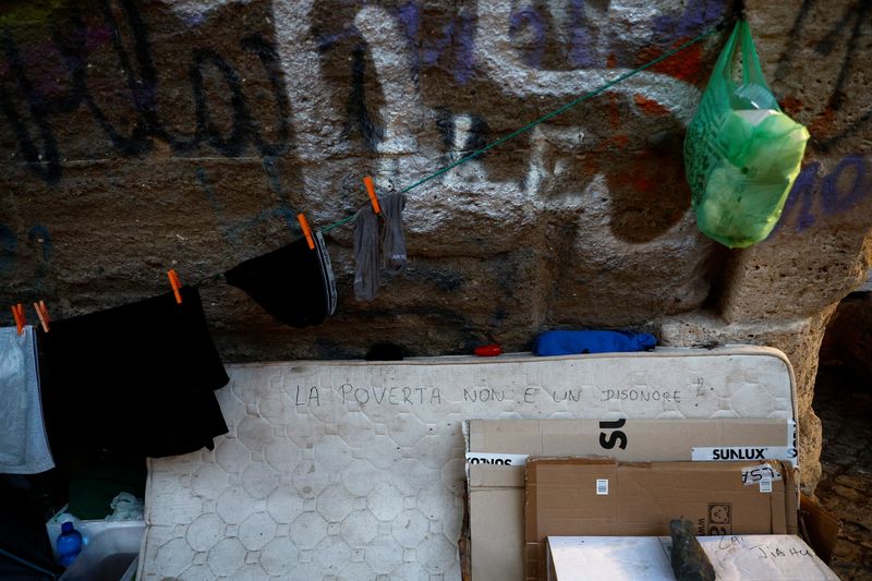 &copy; Reuters. Una scritta su un materasso dice "La povertà non è un disonore" mentre gli operatori della Croce Rossa controllano i senzatetto, durante un'ondata di caldo in tutta Italia, a Roma, 21 luglio 2023. REUTERS/Guglielmo Mangiapane
