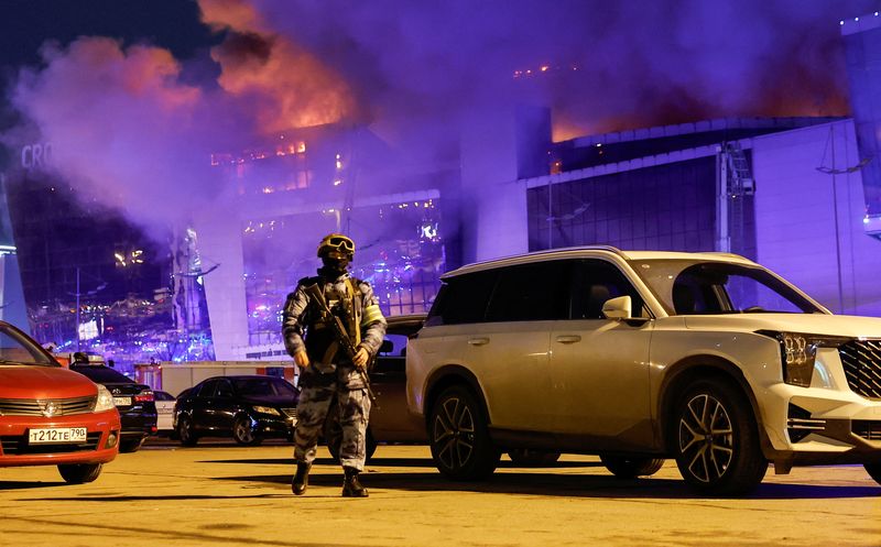 &copy; Reuters. A Russian law enforcement officer walks at a parking area near the burning Crocus City Hall concert venue following a shooting incident, outside Moscow, Russia, March 22, 2024. REUTERS/Maxim Shemetov