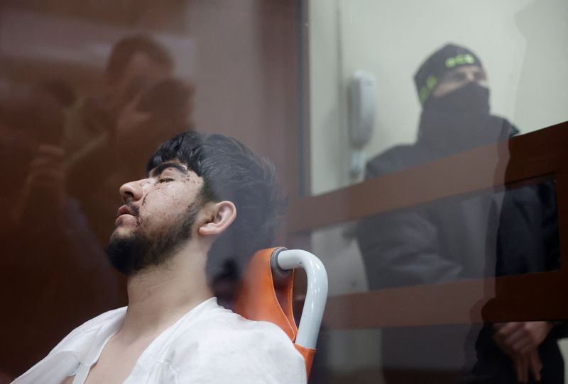 &copy; Reuters. Muhammadsobir Fayzov, a suspect in the shooting attack at the Crocus City Hall concert venue, sits in a medical transport chair behind a glass wall of an enclosure for defendants before a court hearing at the Basmanny district court in Moscow, Russia Marc