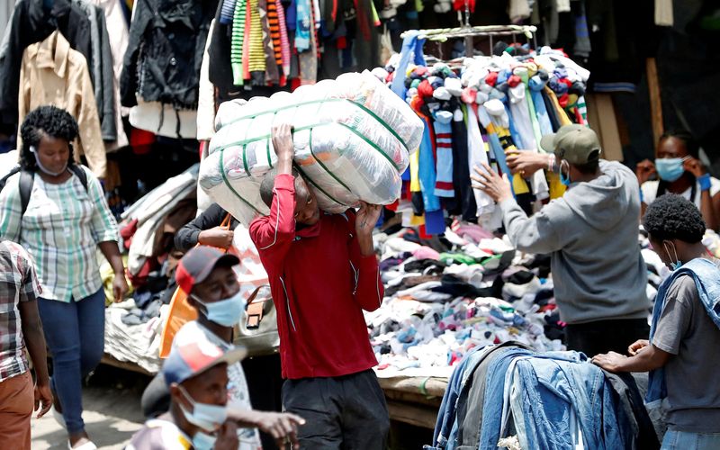 &copy; Reuters. FILE PHOTO: A worker carries a bale of imported second-hand clothes past displayed apparel, amid the coronavirus disease (COVID-19) outbreak at the Gikomba market in Nairobi, Kenya September 18, 2020. REUTERS/Thomas Mukoya/File Photo