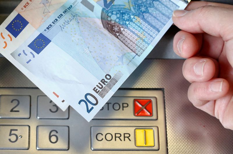 &copy; Reuters. Una donna tiene in mano una banconota da 20 e 50 euro davanti a un bancomat. REUTERS/Thomas Hodel