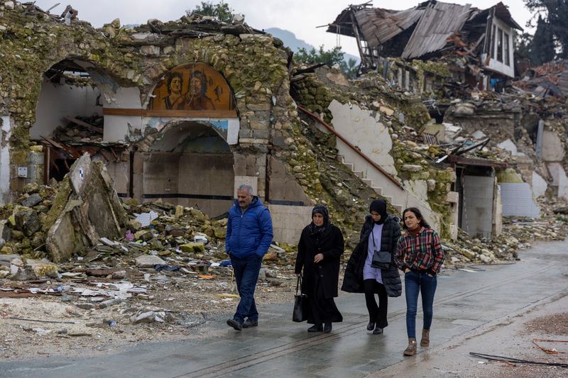 &copy; Reuters. FILE PHOTO: People walk past houses destroyed by last year's earthquake, in Hatay, Turkey, February 5, 2024. The magnitude 7.8 tremor that struck in the early hours of Feb. 6, 2023, levelled towns and city swathes in the country's southeast. It killed mor