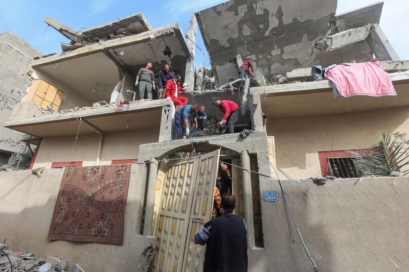 © Reuters. أشخاص يحاولون إنزال أحد القتلى الفلسطينيين، جراء غارة إسرائيلية على منزل في رفح جنوبي قطاع غزة، داخل كيس أسود من الطابق العلوي بالمنزل يوم الأربعاء. تصوير: أحمد زقوت - رويترز