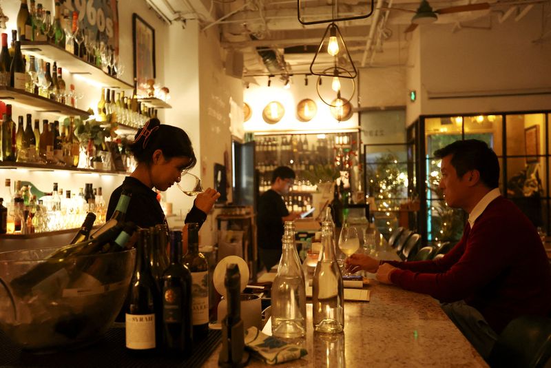 © Reuters. A staff member sniffs wine in a glass while a customer watches at Trio Wine Bar in Beijing, China November 1, 2023. REUTERS/Florence Lo/File Photo