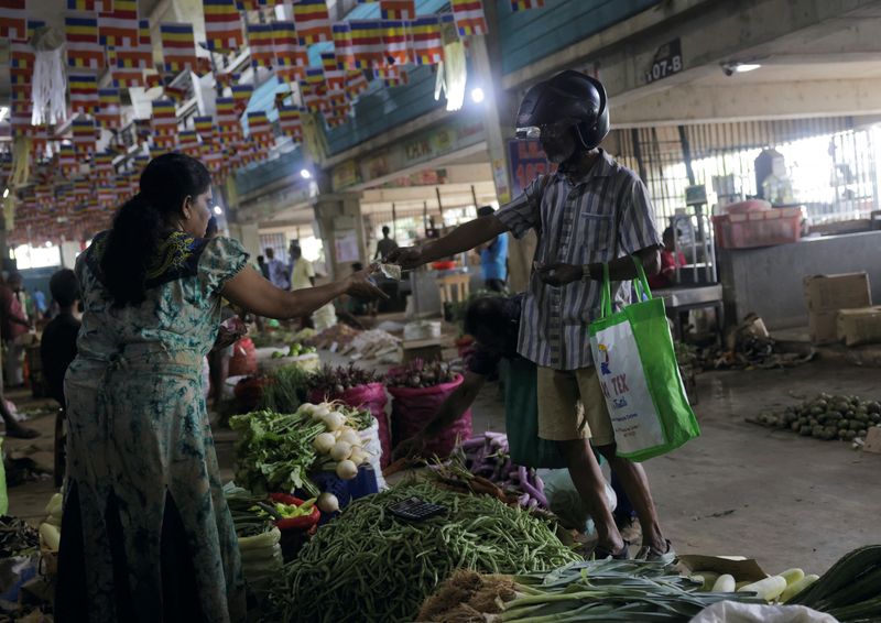 &copy; Reuters. FILE PHOTO: A customer pays for the vegetables he bought at a stall at a main market in Colombo, Sri Lanka June 1, 2023. REUTERS/Dinuka Liyanawatte/File Photo