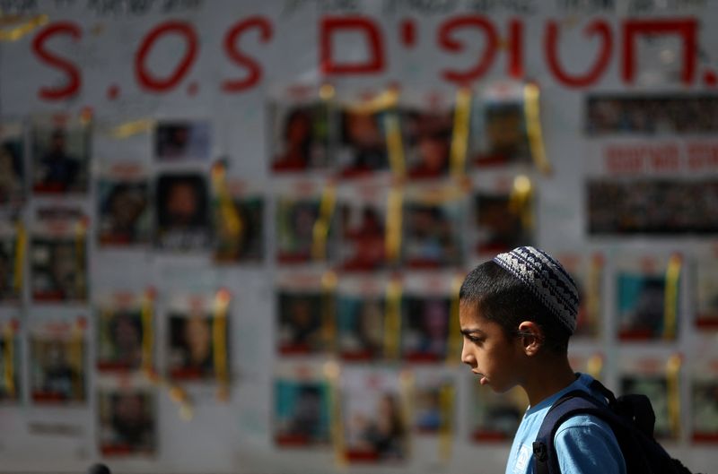 &copy; Reuters. Un garçon passe devant des affiches montrant des photos d'otages enlevés lors de l'attaque meurtrière du 7 octobre contre Israël par le groupe islamiste palestinien Hamas depuis Gaza, à Tel Aviv, Israël. /Photo prise le 28 mars 2024/REUTERS/Hannah M