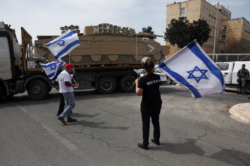 &copy; Reuters. Des manifestants tenant des drapeaux israéliens à côté d'une maquette de véhicule militaire, alors qu'ils réclament l'égalité dans le service militaire israélien, à Jérusalem. /Photo prise le 26 mars 2024/REUTERS/Ronen Zvulun