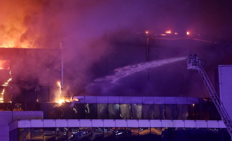 &copy; Reuters. أفراد من فرق الإنقاذ يحاولون إخماد النيران المشتعلة في قاعة (كروكوس سيتي) للحفلات الموسيقية خارج موسكو عقب واقعة إطلاق نار داخلها يوم 22 مارس