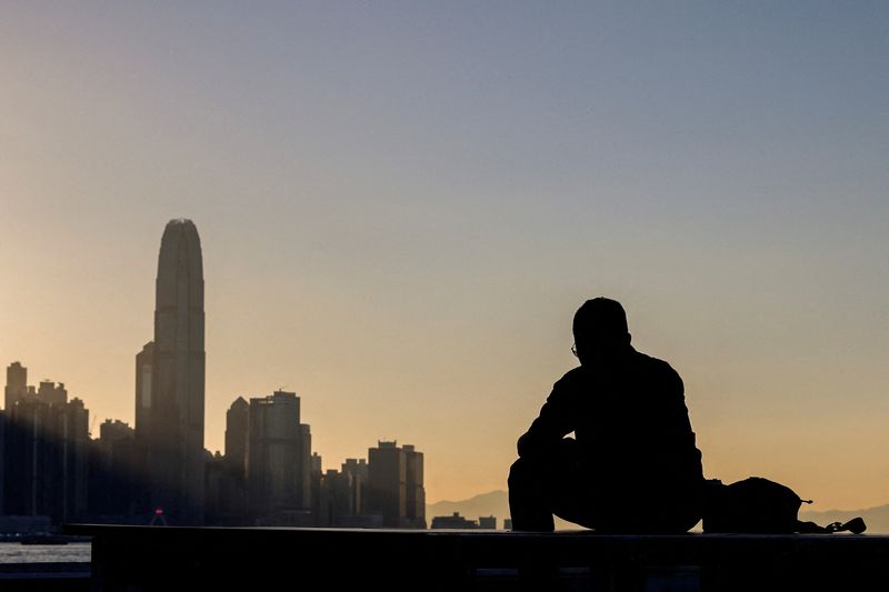 © Reuters. A man sits by the waterfront with the skyline buildings across Victoria Harbor in Hong Kong, China October 24, 2023. REUTERS/Tyrone Siu/File Photo