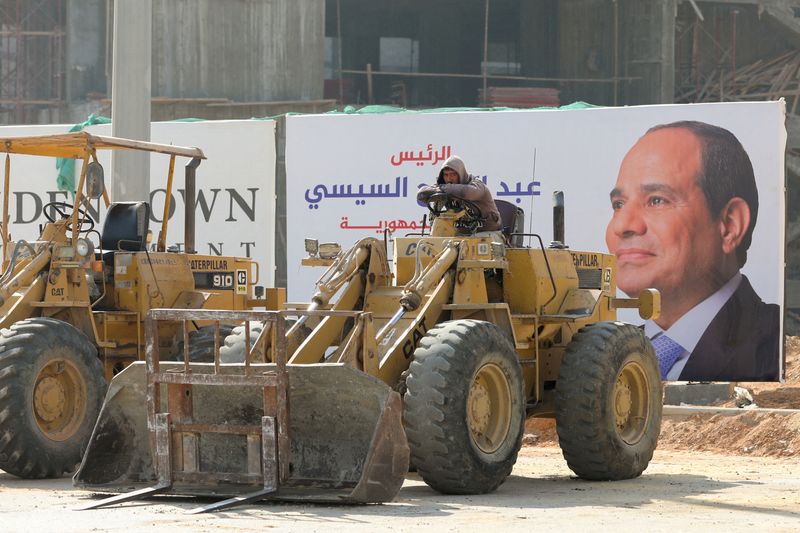 &copy; Reuters. شخص يجلس داخل جرافة بالقرب من لافتة تحمل صورة الرئيس المصري عبد الفتاح السيسي في العاصمة الإدارية الجديدة شرق القاهرة يوم 12 ديسمبر كانون ال