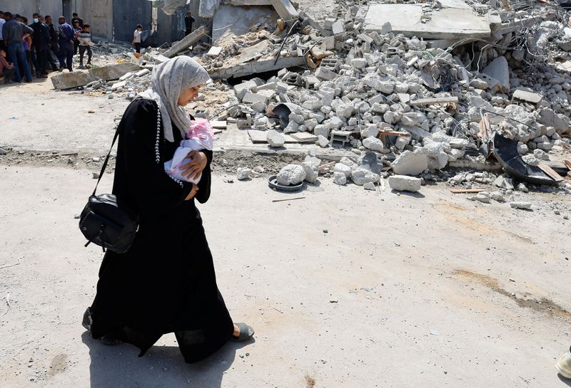 &copy; Reuters. امرأة تحمل رضيعا تسير عند موقع قصف إسرائيلي استهدف مبنى في رفح بجنوب قطاع غزة يوم الثلاثاء. تصوير: محمد سالم - رويترز