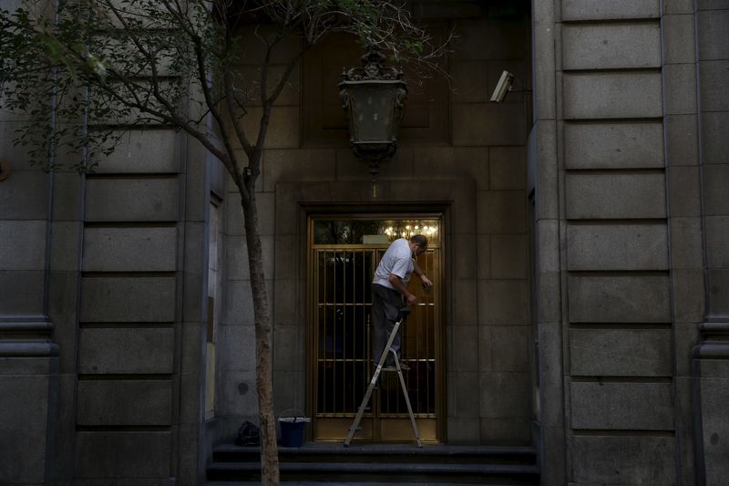 &copy; Reuters. Un homme travaille en nettoyant la porte d'entrée d'un bâtiment. /Photo prise le 29 juillet 2015/REUTERS/Susana Vera