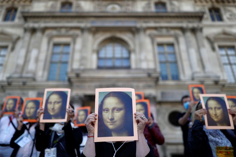 &copy; Reuters. Des guides touristiques parisiens tiennent des affiches représentant la Joconde de l'artiste Léonard de Vinci. /Photo d'archive/REUTERS/Christian Hartmann