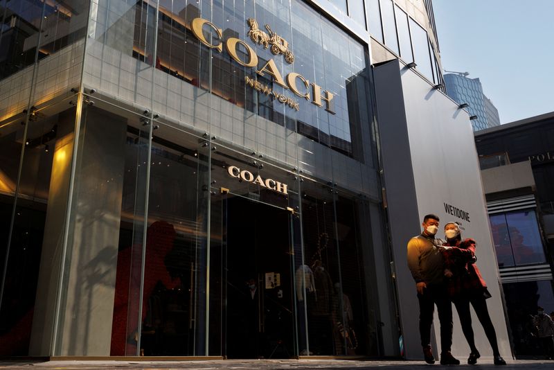 © Reuters. FILE PHOTO: People walk past a store of the Coach luxury fashion retailer in a shopping district in Beijing, China, October 19, 2022. REUTERS/Thomas Peter/File Photo