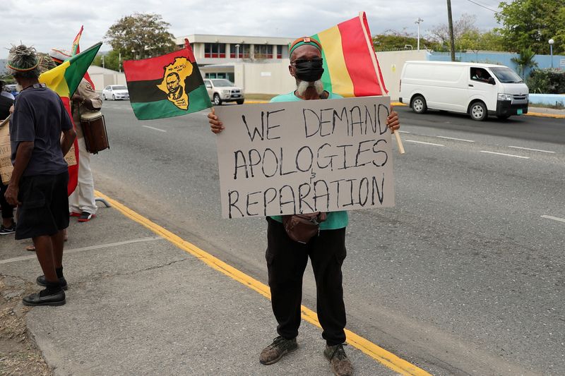 &copy; Reuters. FILE PHOTO: A protester holds a sign during a rally to demand that the United Kingdom make reparations for slavery, ahead of a visit to Jamaica by the Duke and Duchess of Cambridge as part of their tour of the Caribbean, outside the British High Commissio