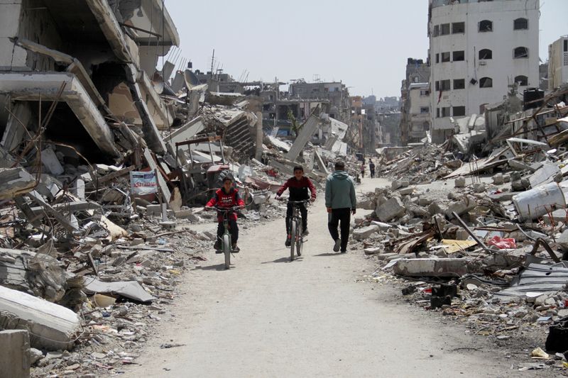 &copy; Reuters. Palestinos andam de bicicleta pelas ruínas de casas e edifícios, destruídos durante a ofensiva militar de Israel na Faixa de Gaza
31/03/2024
REUTERS/Mahmoud Issa