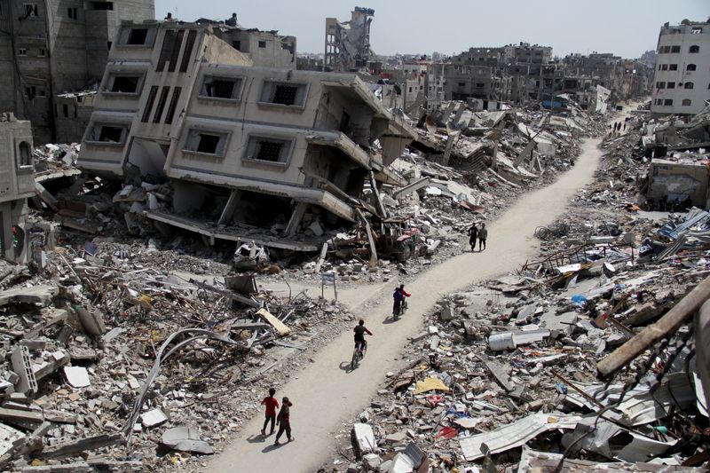 &copy; Reuters. FOTO DE ARCHIVO. Palestinos montan en bicicleta junto a las ruinas de casas y edificios destruidos durante la ofensiva militar israelí, en medio del actual conflicto entre Israel y Hamás, en el norte de la Franja de Gaza. 31 de marzo de 2024. REUTERS/Ma