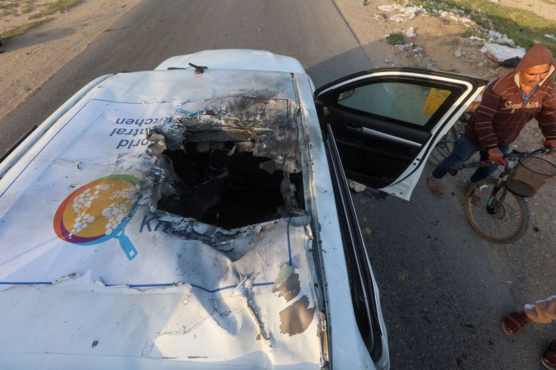&copy; Reuters. فلسطيني يقود دراجة هوائية بجوار سيارة قُتل فيها موظفون من منظمة ورلد سنترال كيتشن الخيرية جراء غارة جوية إسرائيلية في دير البلح وسط قطاع غز