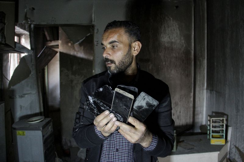 &copy; Reuters. FILE PHOTO: Palestinian owner of mobile phone business Salem Awad Rab'a holds damaged phones inside his shop which was destroyed in an Israeli strike, in Jabalia in the northern Gaza Strip March 31, 2024. REUTERS/Mahmoud Issa/File Photo