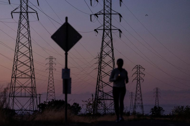 © Reuters. FILE PHOTO: Một người phụ nữ chạy bộ bên đường dây điện ở Mountain View, California, Hoa Kỳ, ngày 17 tháng 8 năm 2022. REUTERS/Carlos Barria/File Photo