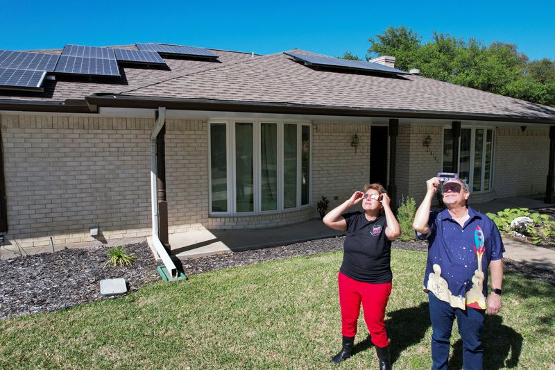 &copy; Reuters. Eclipse chaser Leticia Ferrer and her husband Daniel Brookshier observe the sun through eclipse glasses, in front of their home in Dallas, Texas, U.S., April 3, 2024. REUTERS/Evan Garcia