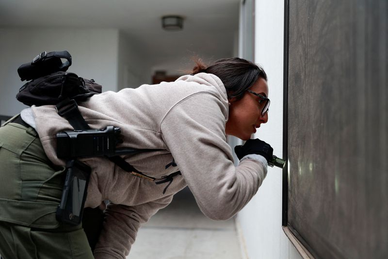 &copy; Reuters. Behavioral health responder Nevada Sanchez, 28, from Albuquerque Community Safety looks through a window of an apartment to see if anyone is inside, in response to a wellness check on two children in Albuquerque, New Mexico, U.S., March 15, 2024.  REUTERS