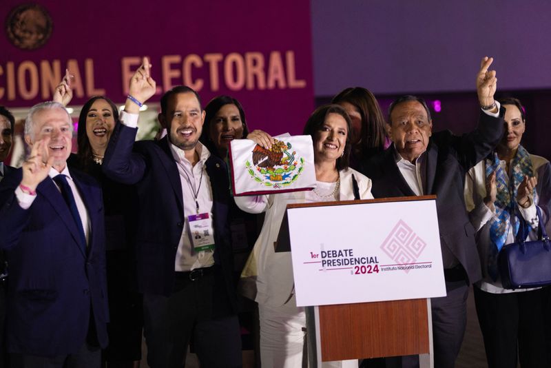 © Reuters. Xochitl Galvez, the presidential candidate of the 'Fuerza y Corazon por Mexico', an alliance of opposition events, reveals the coat of arms of Mexico on the Mexican flag while standing alongside Santiago Creel, member of the National Action Celebration, National Action Celebration President Marko Antonio Cortes Mendoza and Celebration of the Democratic Revolution President Jesus Zambrano, after attending the first presidential debate on the facilities of the National Electoral Institute (INE), in Mexico Metropolis, Mexico, April 7, 2024. REUTERS/Quetzalli Nicte-Ha