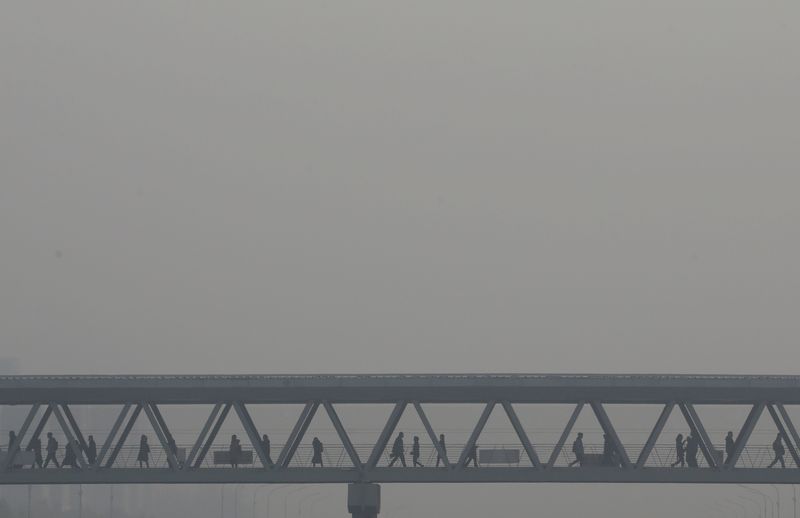 &copy; Reuters. FILE PHOTO: People walk on a pedestrian bridge as heavy smog blankets China's capital after the city issued its first air pollution alert for the winter season, in Beijing, China November 26, 2018. REUTERS/Jason Lee/File Photo