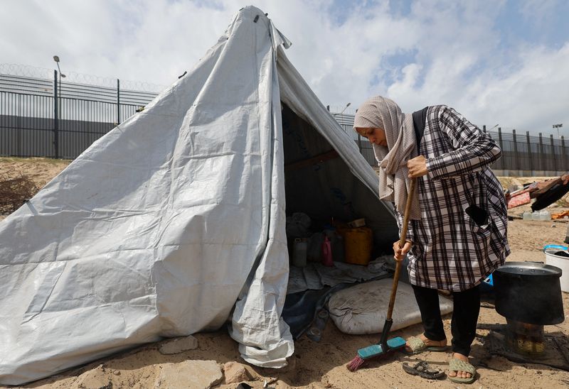 &copy; Reuters. Una mujer barre junto a una tienda de campaña, mientras los palestinos desplazados, que huyeron de sus casas debido a los ataques israelíes, se refugian en un campamento de tiendas de campaña, en medio del conflicto en curso entre Israel y el grupo isl