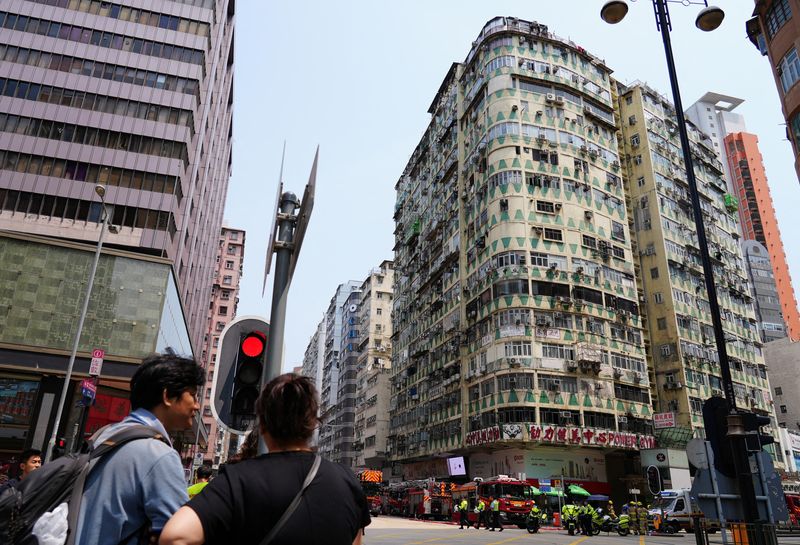 &copy; Reuters. أشخاص ينظرون على مبنى السكني حيث اندلع حريق في صالة الألعاب الرياضية في منطقة كولون في هونج كونج بالصين بتاريخ العاشر من أبريل نيسان 2024. تصو