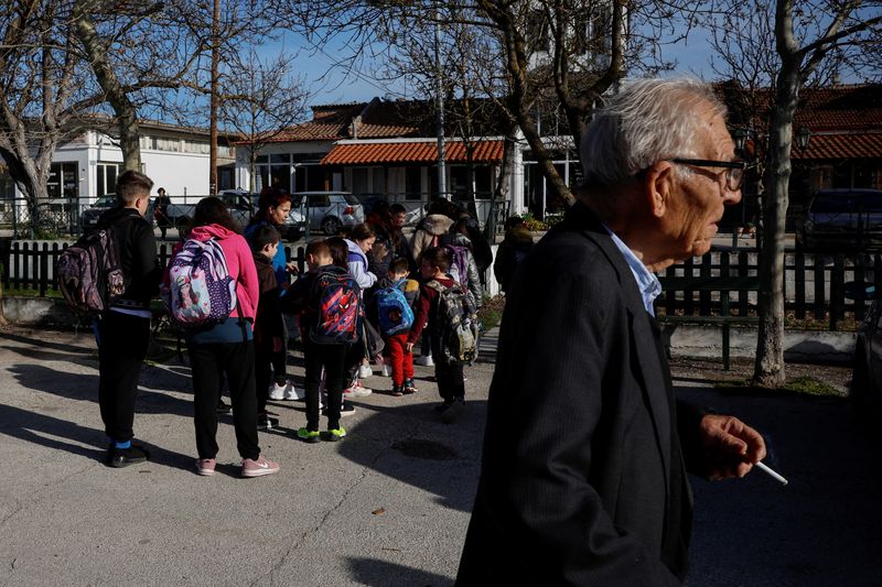 &copy; Reuters. A man walks pasts schoolchildren from nearby villages waiting to be escorted to the the primary school, which serves 17 villages, in the village of Dikaia, Greece, March 29, 2024. The population of Orestiada, a crop-growing area bordering Turkey and Bulga