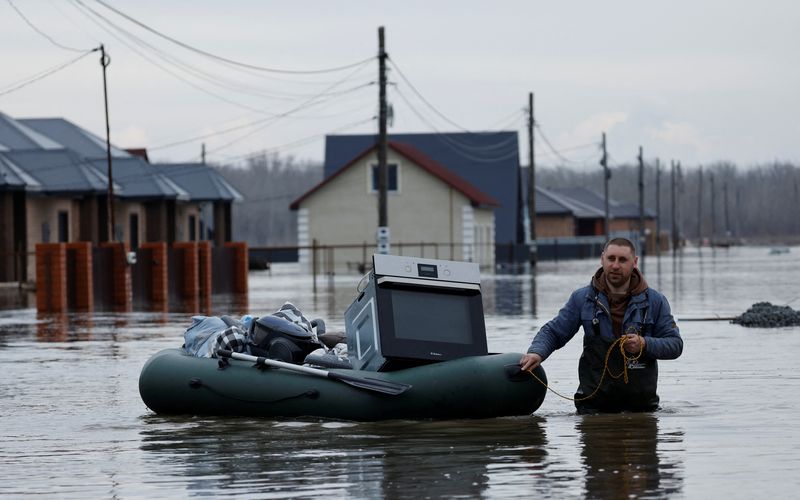 © Reuters. A man tows an inflatable boat with his belongings along a flooded street in the settlement of Ivanovskoye, Orenburg region, Russia, April 10, 2024. REUTERS/Maxim Shemetov