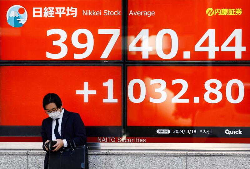 &copy; Reuters. رجل يقف أمام شاشة إلكترونية تعرض بيانات المؤشر نيكي الياباني خارج شركة للوساطة المالية في طوكيو يوم 18 مارس آذار 2024. تصوير: كيم كيونج هوون - رو