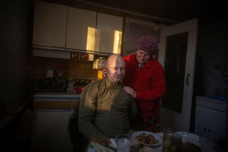 © Reuters. Nadiya Pavlivna holds her grandson Oleksandr Revtiukh, 33, a Ukrainian serviceman who lost his left arm and most of his left leg in multiple mine blasts in 2023, at her house during his first visit after his injury, amid Russia's attack on Ukraine, in his hometown of Nizhyn, Ukraine, November 24, 2023. Revtiukh is close to his family, and recently visited his parents' home in Nizhyn, northeast of Kyiv. Waiting outside, his grandmother wept as she embraced Revtiukh, whom she had not seen since his arm and leg were torn off in two separate mine blasts. 