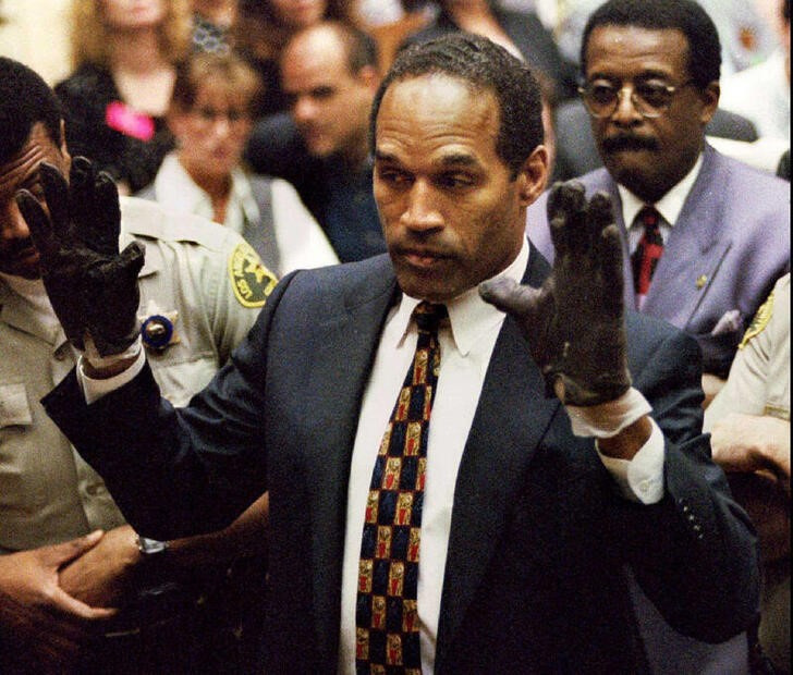 © Reuters. FOTO DE ARCHIVO: O.J. Simpson, con los guantes manchados de sangre encontrados por la Policía de Los Ángeles e introducidos como prueba en el juicio por asesinato de su exesposa, muestra sus manos al jurado a petición del fiscal Christopher Darden 
15 de junio de 1995
REUTERS/Sam Mircovich/
