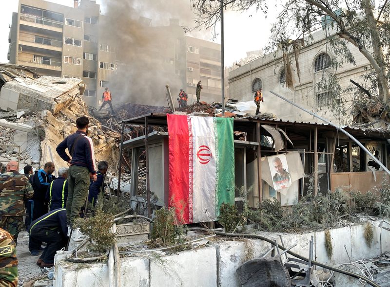 &copy; Reuters. علم إيراني معلق بينما يتصاعد الدخان جراء ما ذكرت وسائل إعلام إيرانية أنها غارة جوية إسرائيلية دمرت مبنى القنصلية الإيرانية بالقرب من السفا