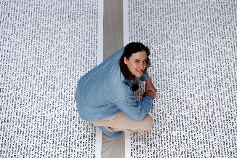 &copy; Reuters. El artista francés Baptiste Chebassier posa en medio de una parte de su obra de arte, realizada con rollos de papel reciclado en los que  escribirá los nombres de 30.249 medallistas olímpicos, en el taller de Chebassier en Saint-Ouen, cerca de París, 