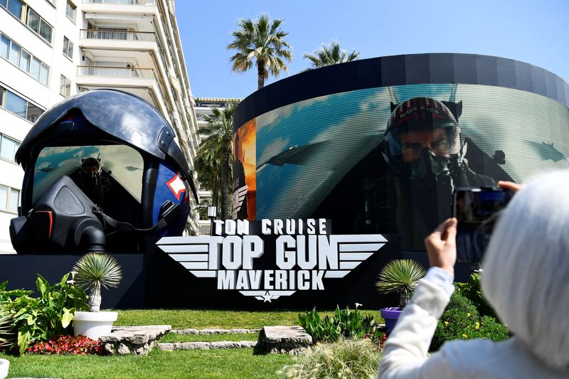 © Reuters. FILE PHOTO: The 75th Cannes Film Festival - The Croisette - Cannes, France, May 18, 2022. A woman takes a photo of a giant advertising pilot helmet broadcasting a movie trailer for the film 