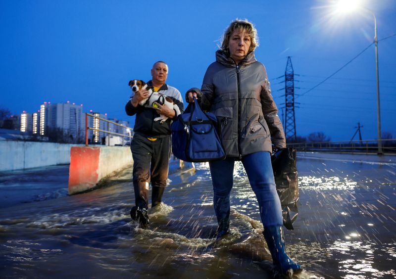 &copy; Reuters. شخصان يسيران في شارع تغمره المياه خلال إجلاء المواطنين من حي سكني في منطقة أورينبورج بروسيا يوم 12 أبريل نيسان 2024. تصوير: ماكسيم شيمتوف - رويت