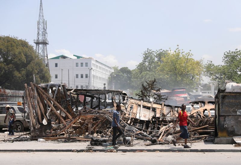 &copy; Reuters. أشخاص يسيرون قرب بقايا حافلات احترقت خلال أعمال عنف في عاصمة هايتي بورت او برنس يوم 25 مارس آذار 2024. تصوير:  تصوير: رالف تيدي إيرول - رويترز