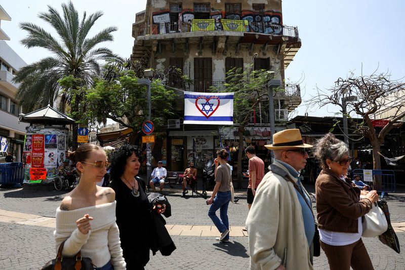&copy; Reuters. La gente camina junto a una bandera israelí con el símbolo de un corazón, después de que Irán lanzó aviones no tripulados y misiles hacia Israel, en Tel Aviv, Israel. 14 de abril de 2024. REUTERS/Hannah McKay 
