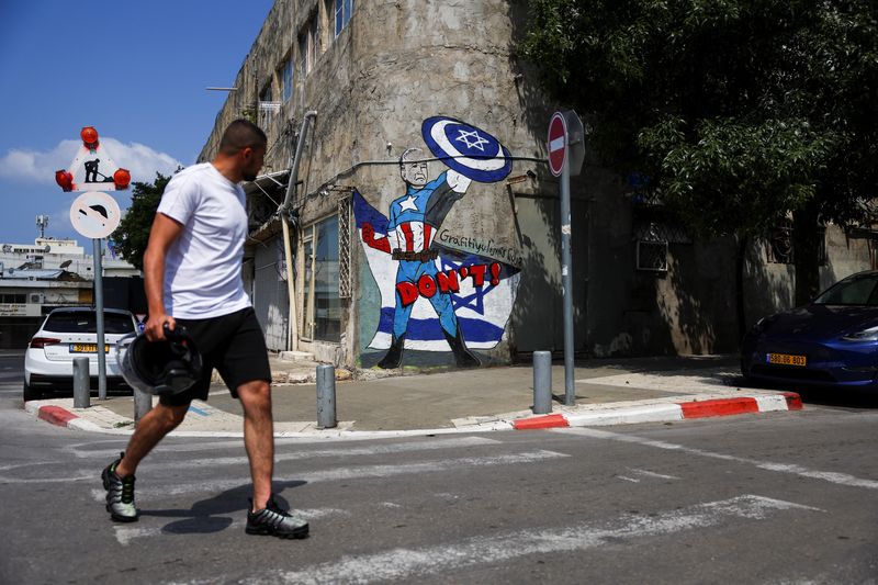 &copy; Reuters. Un hombre pasa junto a una pintada que representa al presidente de Estados Unidos, Joe Biden, como un superhéroe en Tel Aviv, Israel. 14 de abril de 2024. REUTERS/Hannah McKay